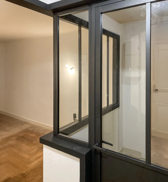 Intérieur moderne avec fenêtre coulissante ouverte à cadre métallique noir donnant sur une pièce adjacente