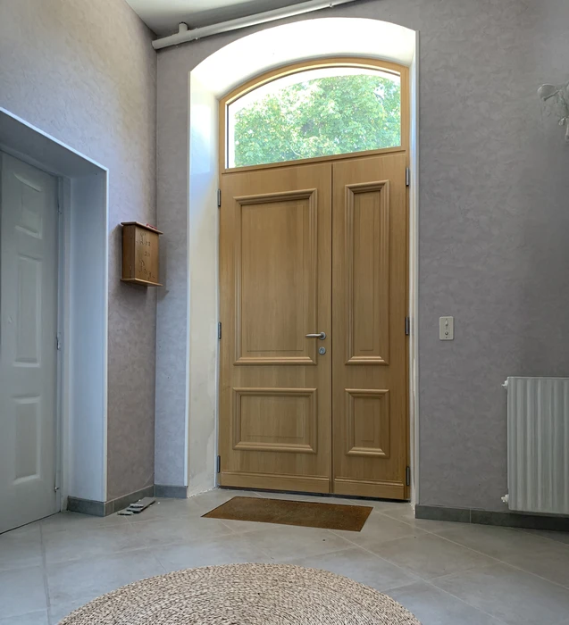 Entrée résidentielle moderne avec double porte en bois massif à panneaux moulurés et imposte vitrée cintrée