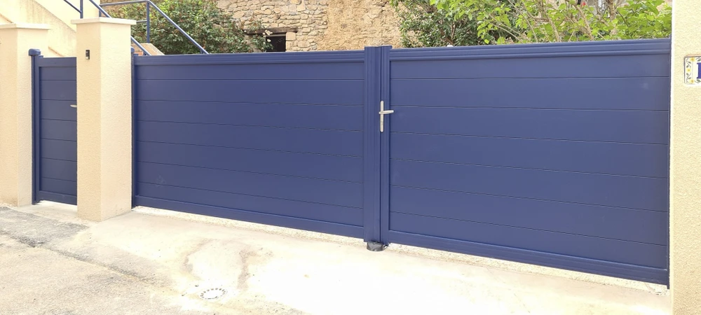Extérieur résidentiel avec portail coulissant motorisé bleu en aluminium laqué, système à lames horizontales pleines pour occultation totale