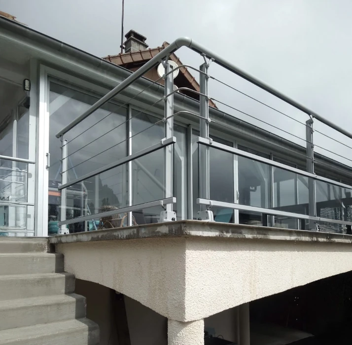 Terrasse extérieure d'immeuble moderne avec garde-corps en acier inoxydable et panneaux vitrés